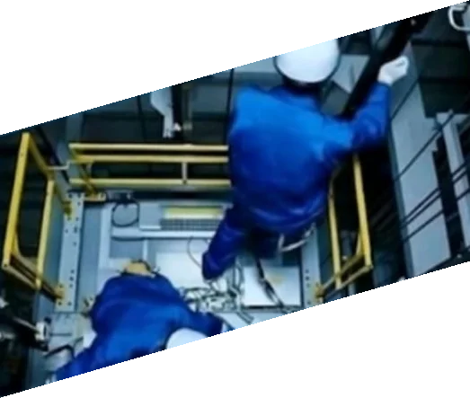 Técnicos trabalhando sobre a cabine, no poço do elevador